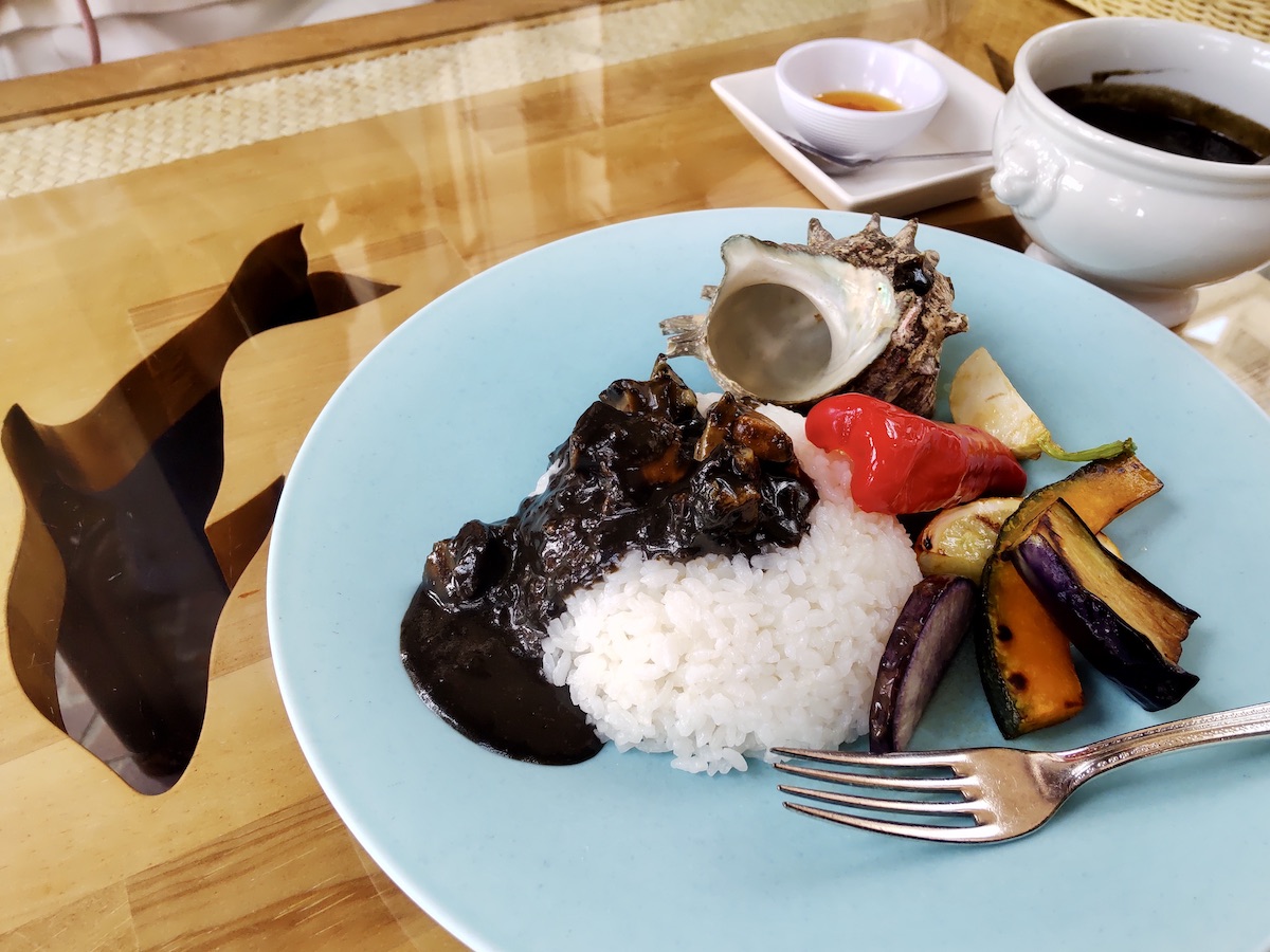 A curry plate decorated with a seashell, served with assorted grilled vegetables
