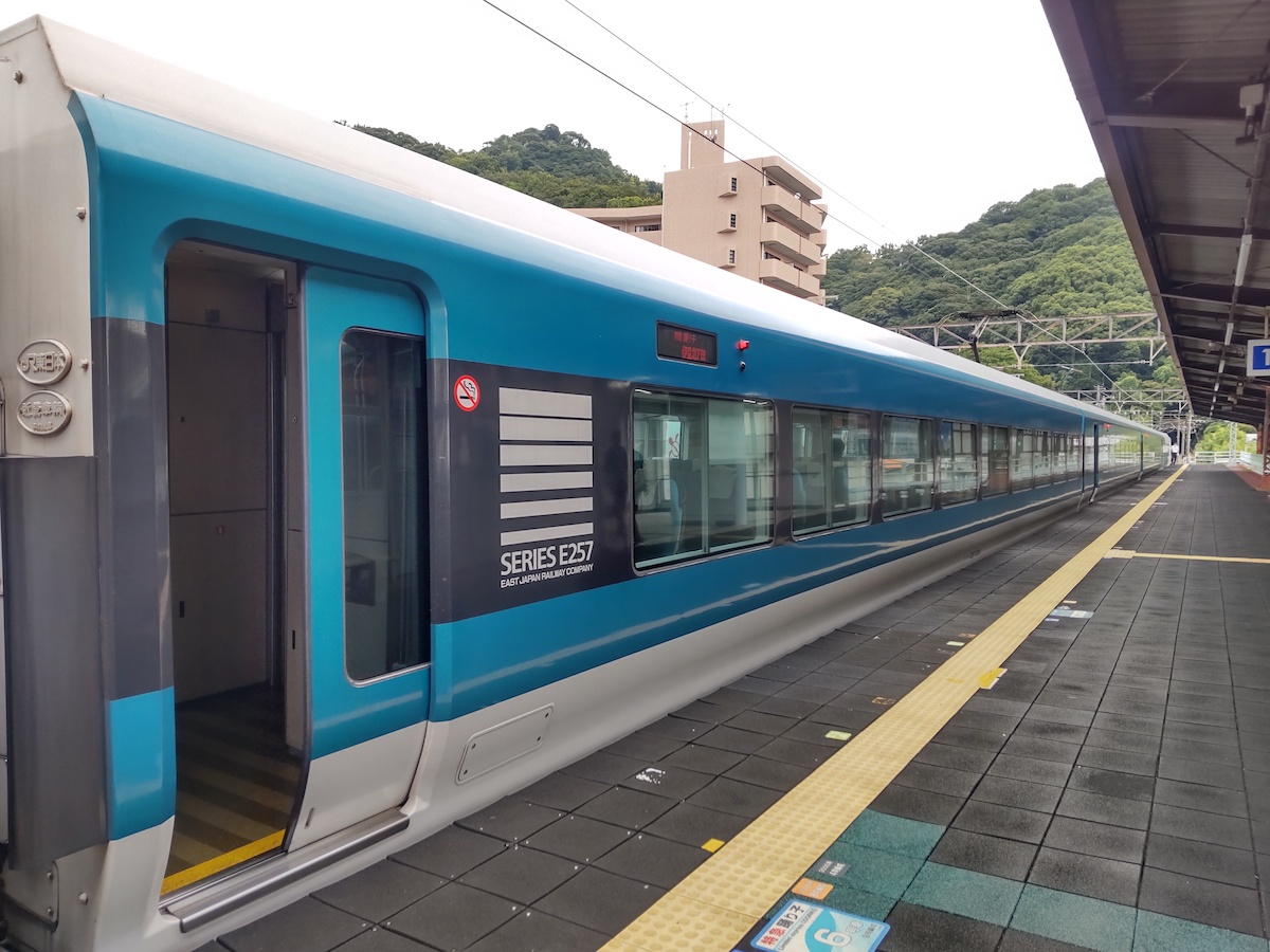 A train with a blue line stopped along a station platform