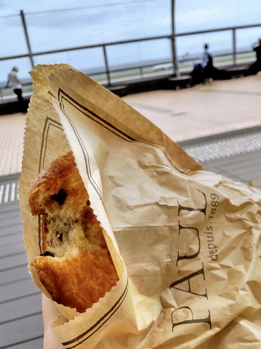 A French pastry from PAUL held at an observation deck overlooking the airport