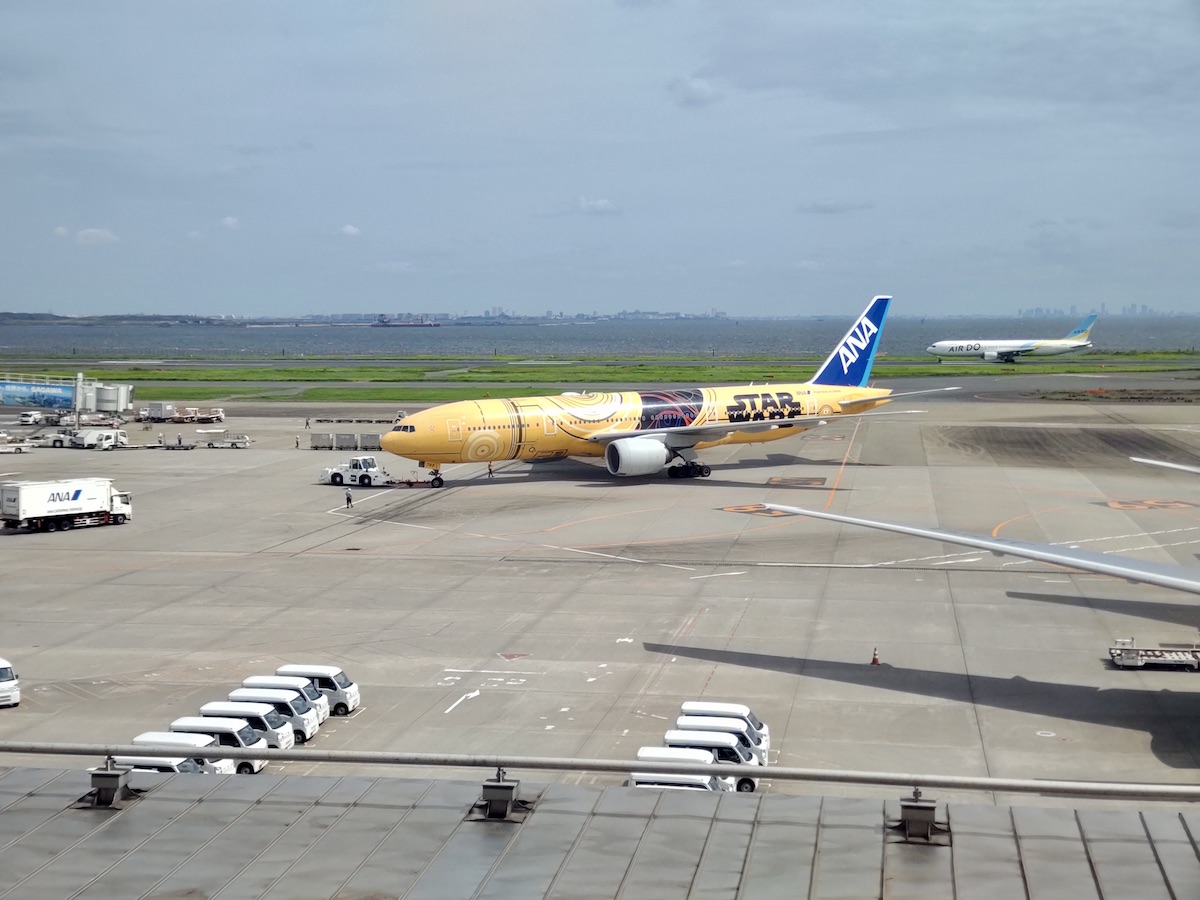 A yellow STAR WARS livery ANA airplane moving across the tarmac at Haneda