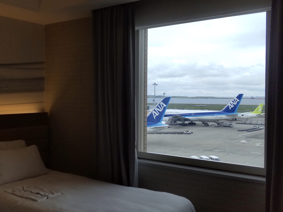 View of airplanes on the runway from a bed inside a hotel room