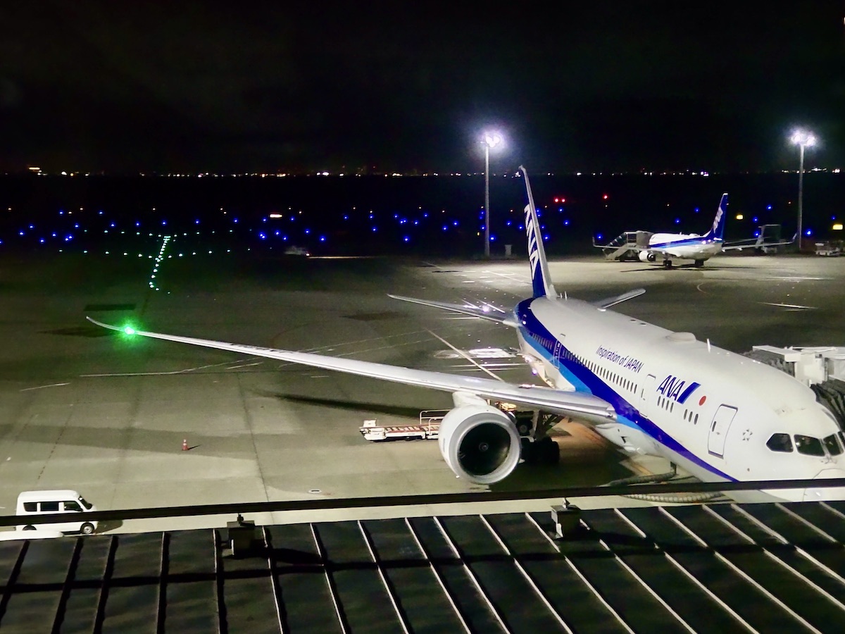 A quiet night view of airplanes parked at Haneda Airport with blue runway lights