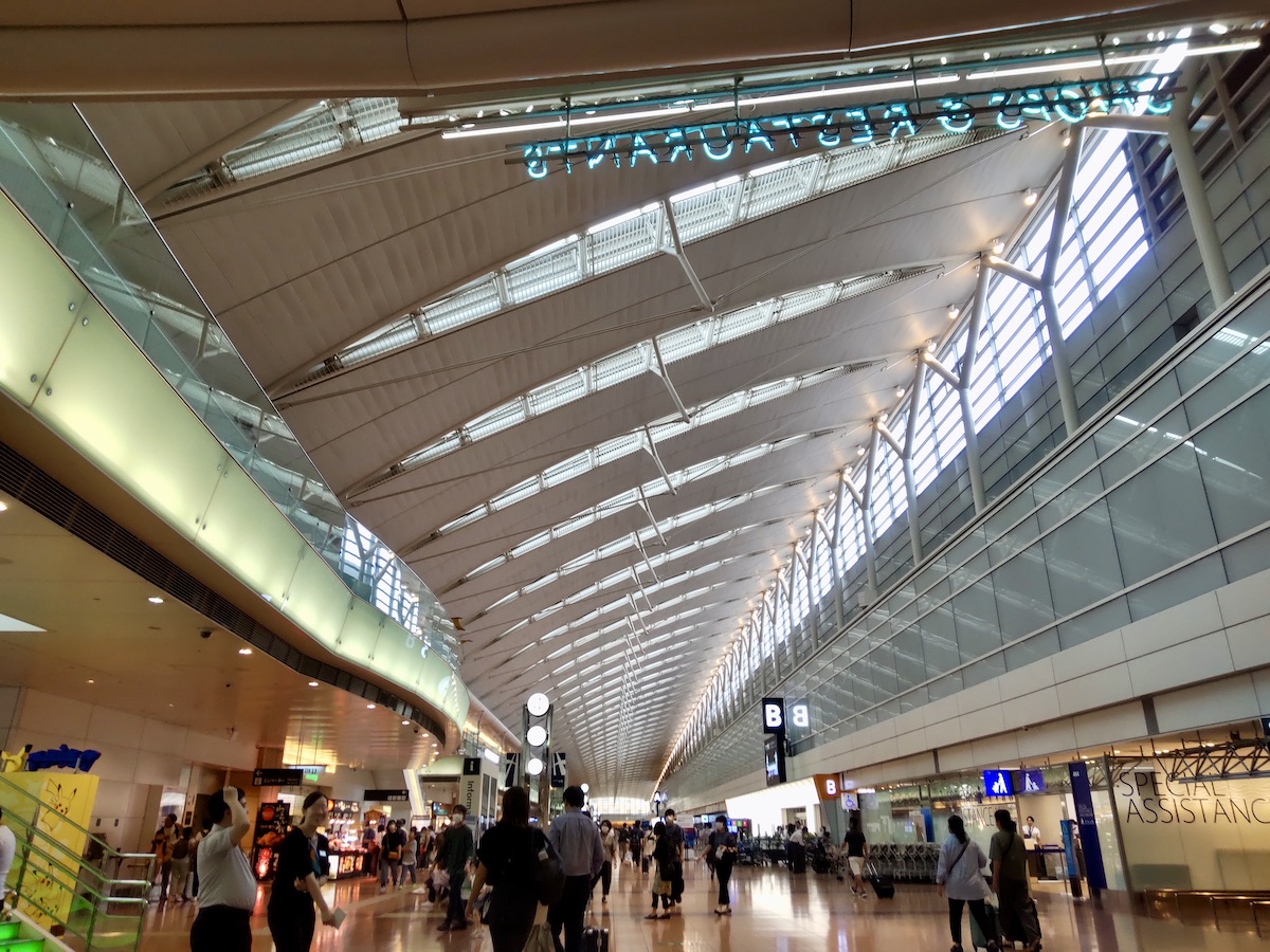 Travelers walking through the spacious departure lobby with high ceilings at Haneda Airport