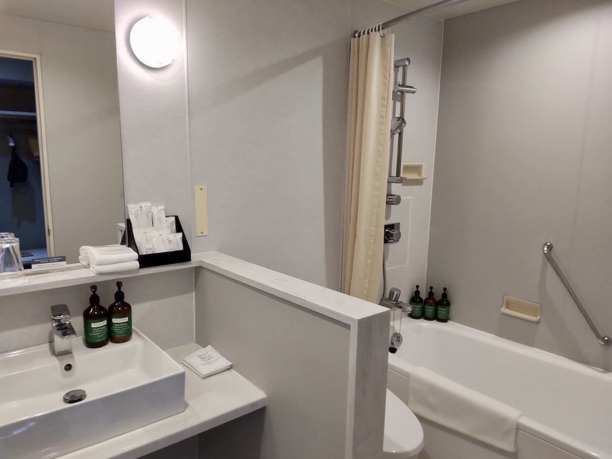 A clean hotel bathroom with a white sink counter next to a bathtub