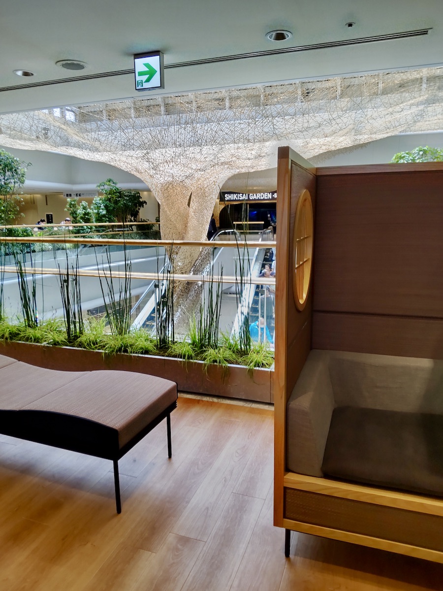 A modern airport public rest area featuring stylish Japanese-style wooden booths and unique ceiling art