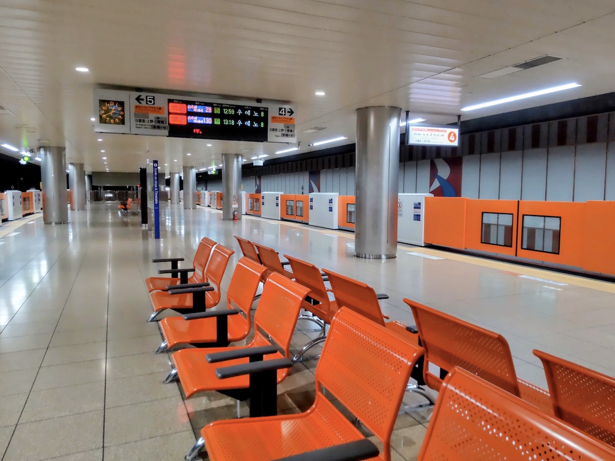 An airport train station platform featuring rows of orange seats and matching platform gates