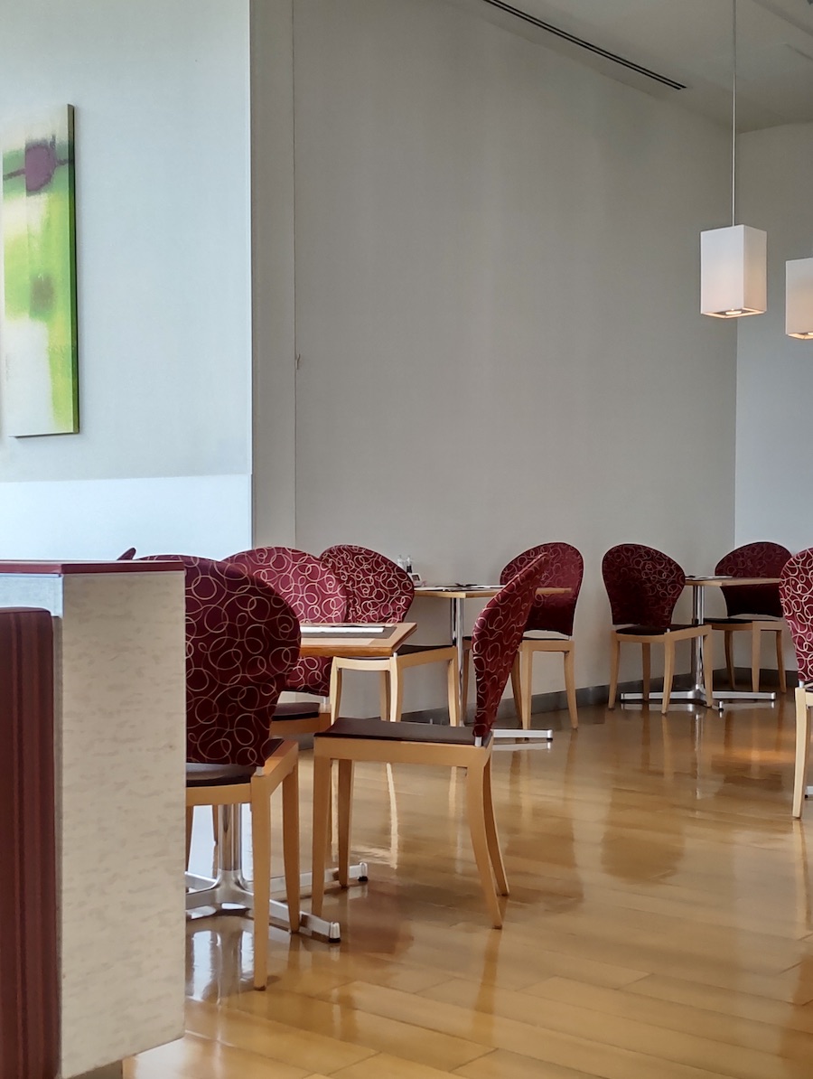 A hotel dining area featuring elegant red patterned chairs and wooden tables