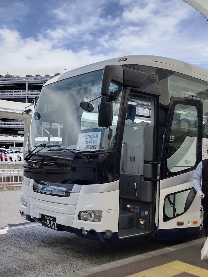 A close-up of a large hotel shuttle bus parked at the airport terminal