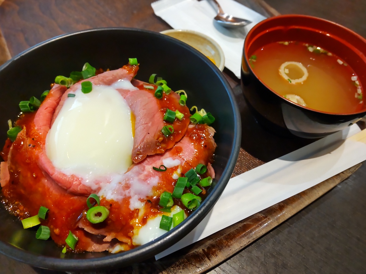A Japanese roast beef rice bowl topped with a soft-boiled egg and miso soup