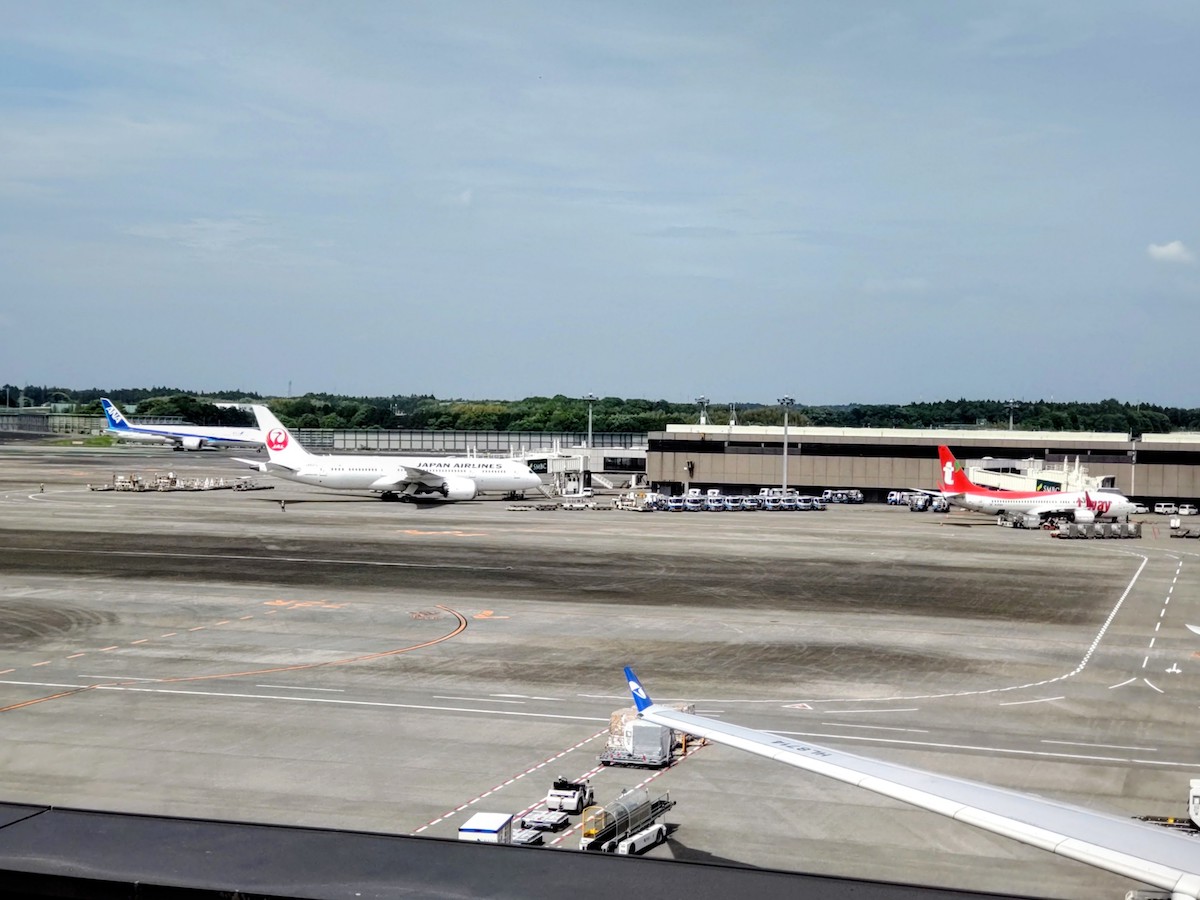 Multiple airplanes parked on the tarmac at an airport under a clear sky