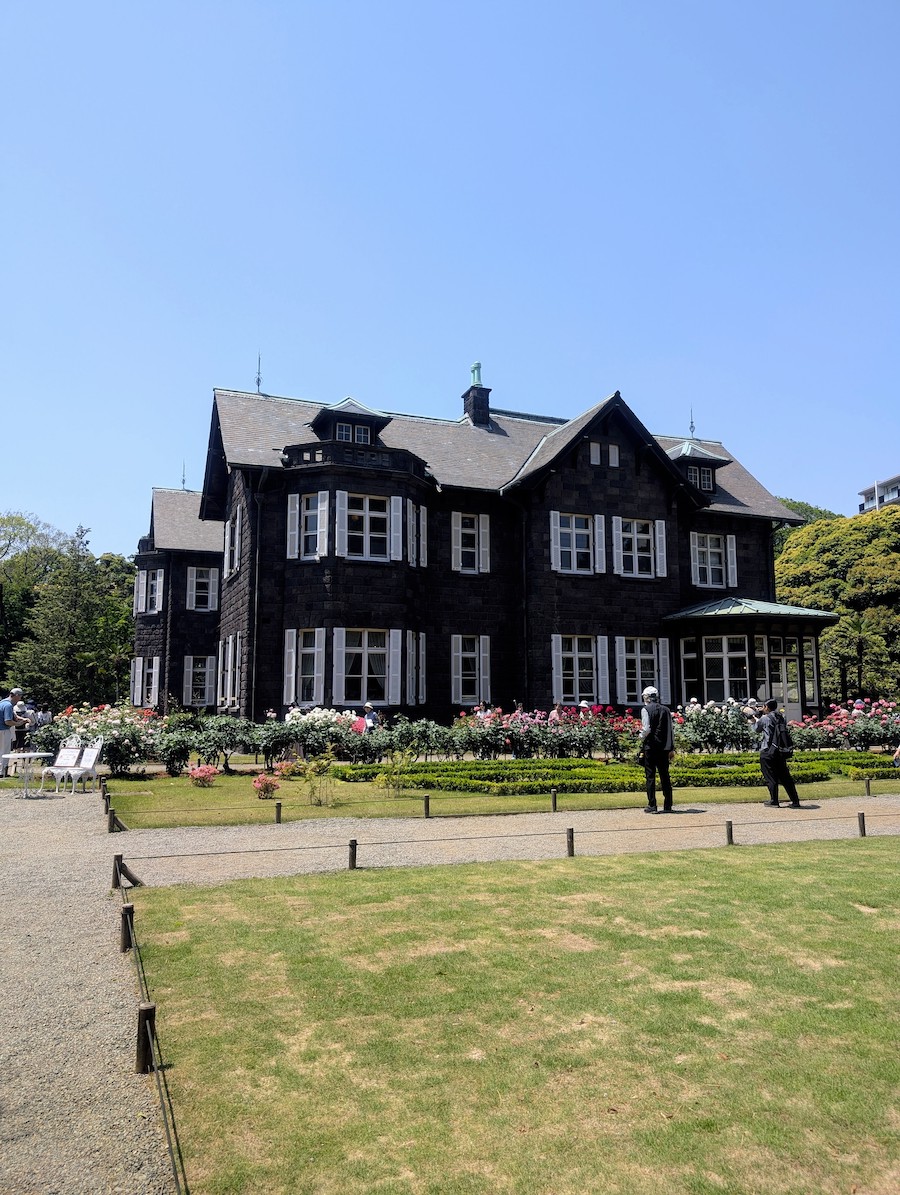 An elegant Western-style building surrounded by colorful roses under a clear blue sky