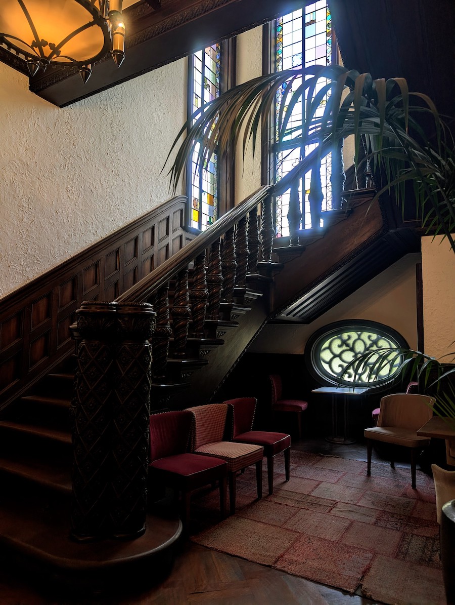 An elegant wooden staircase with beautiful stained glass windows in a historic building