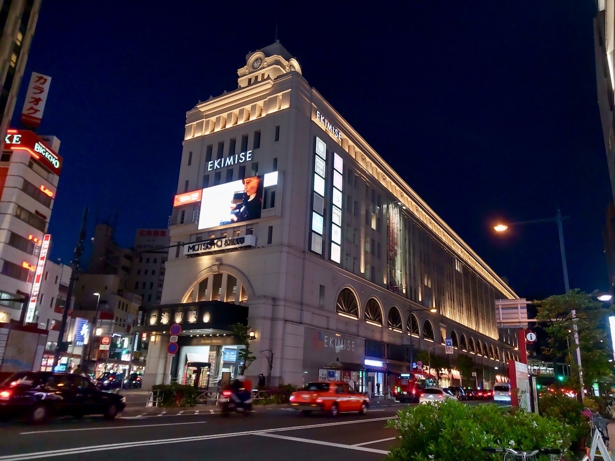 Illuminated historic Asakusa Station building with traffic passing by at night