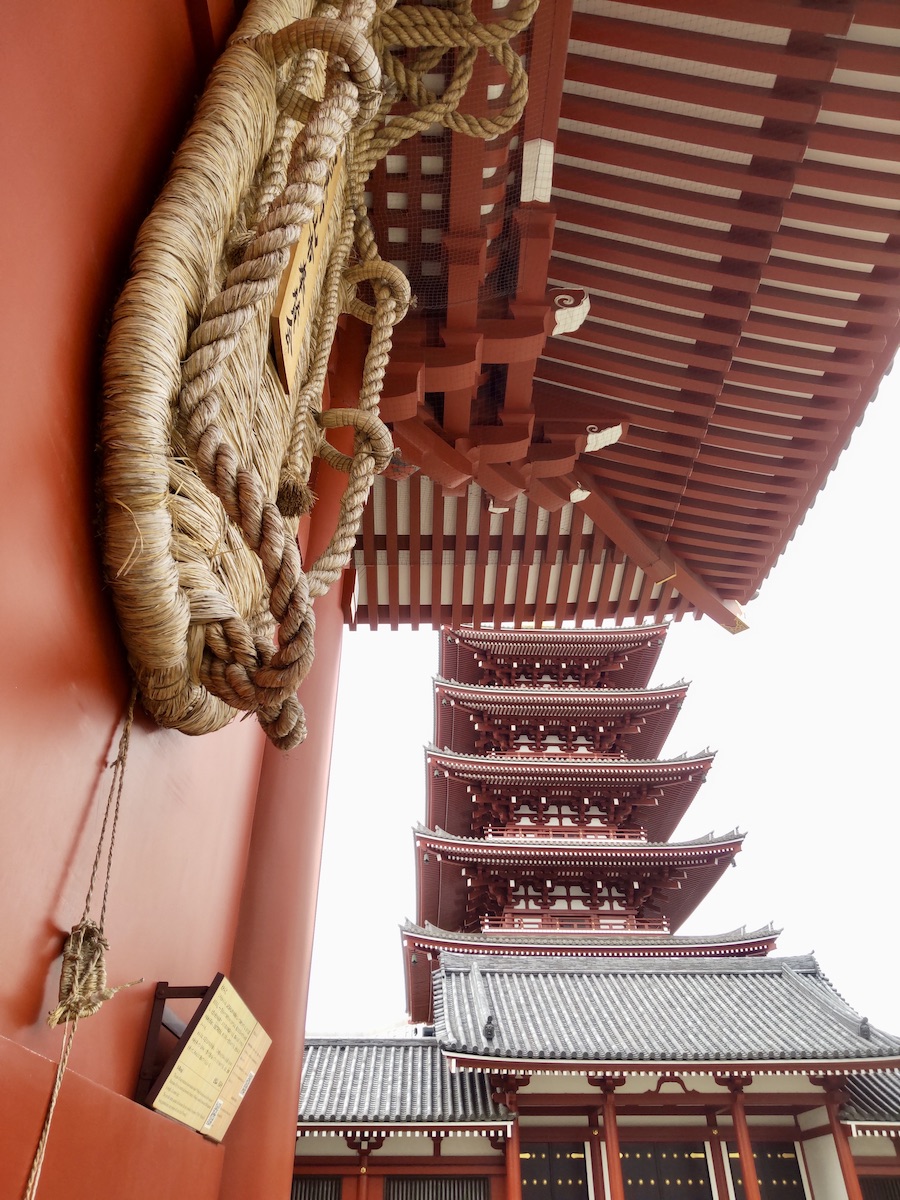 A giant straw sandal on a red gate with a five-story pagoda background