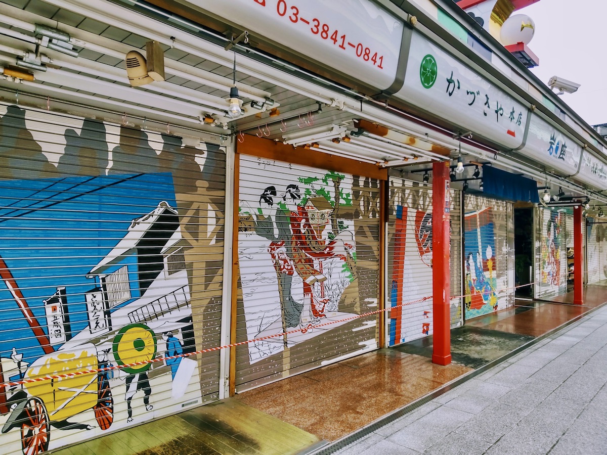 Closed shop shutters along Nakamise Street decorated with colorful Japanese artwork