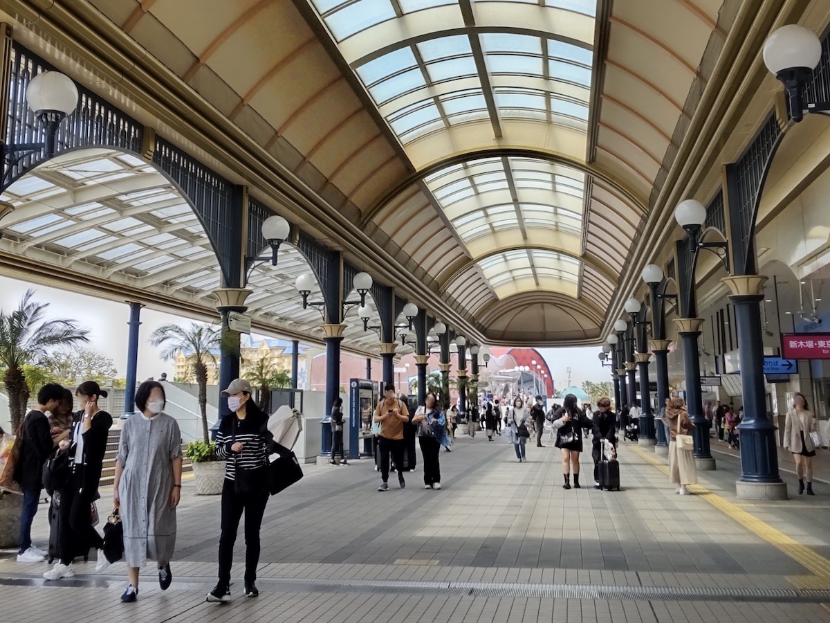 Pedestrians walking under a grand arched covered walkway at Maihama Station