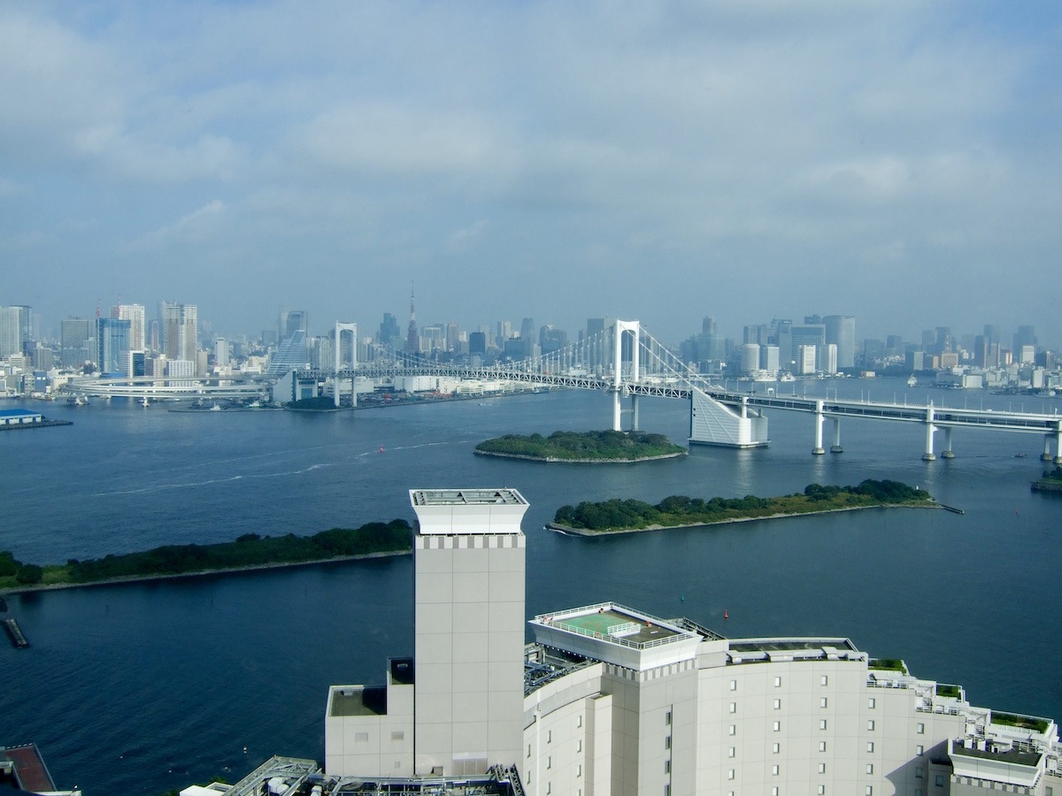 Panoramic aerial view of Rainbow Bridge and Tokyo Bay under a blue sky