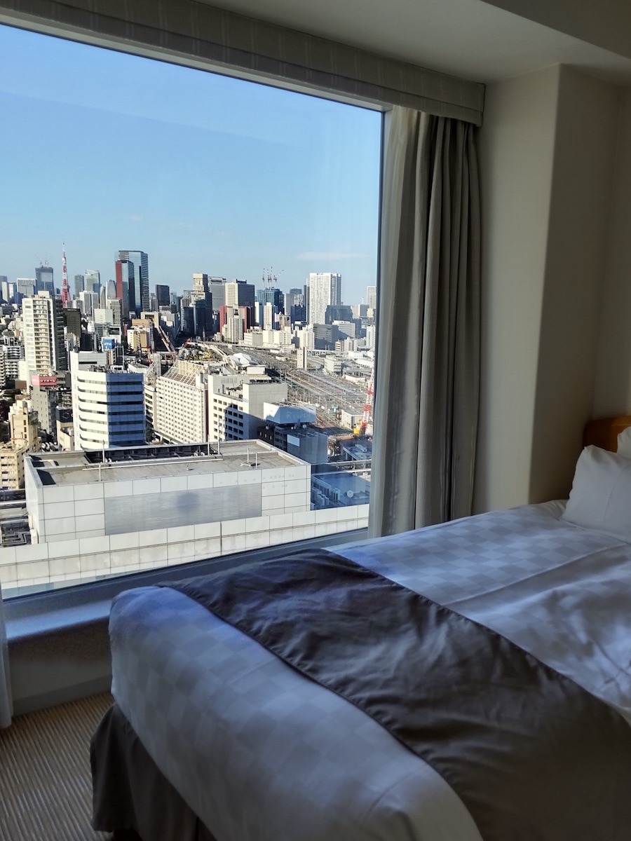 A hotel room window overlooking Tokyo Tower and the cityscape under clear skies