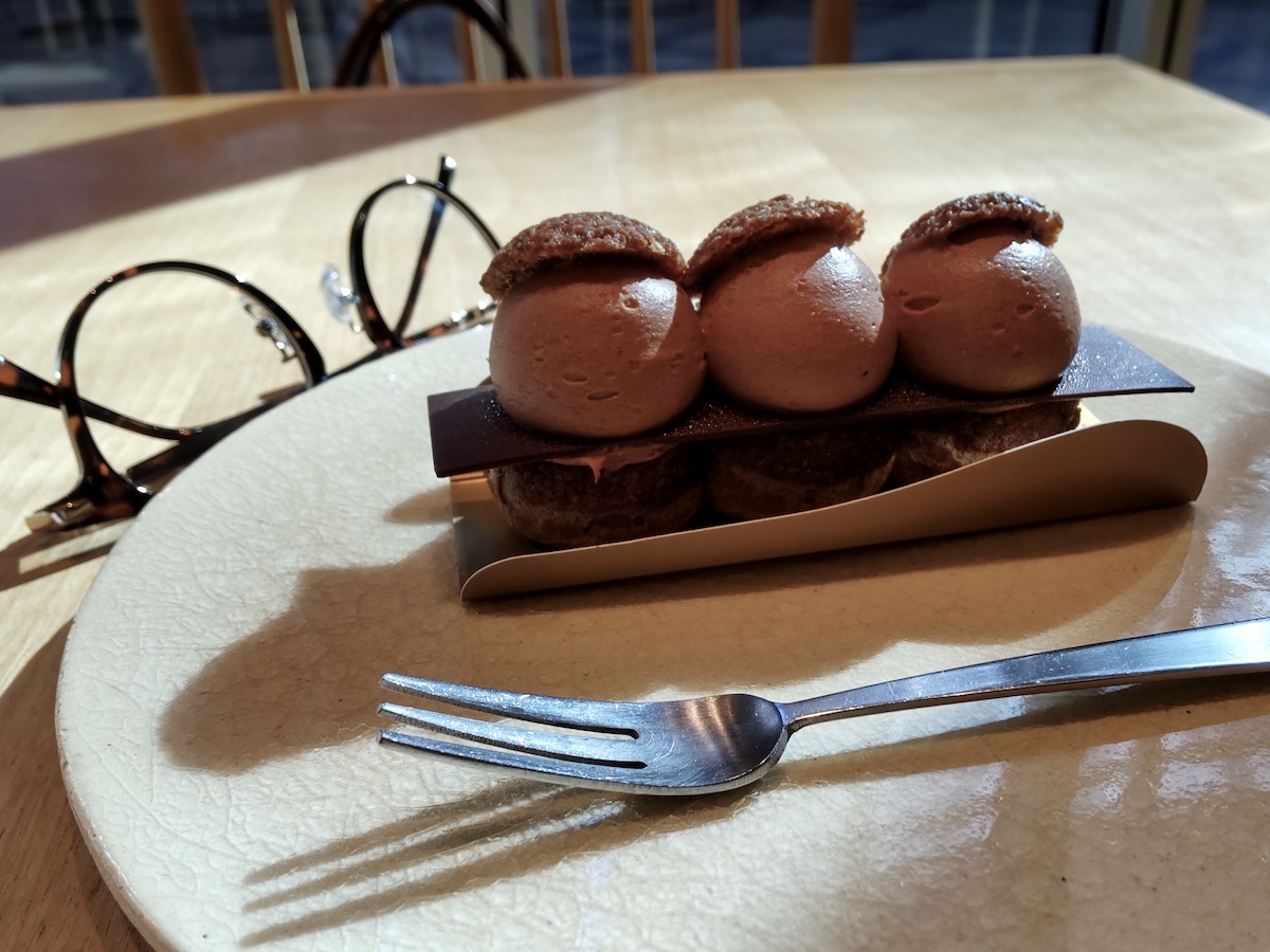 Elegant multi-layered chocolate dessert on a ceramic plate with a fork and glasses