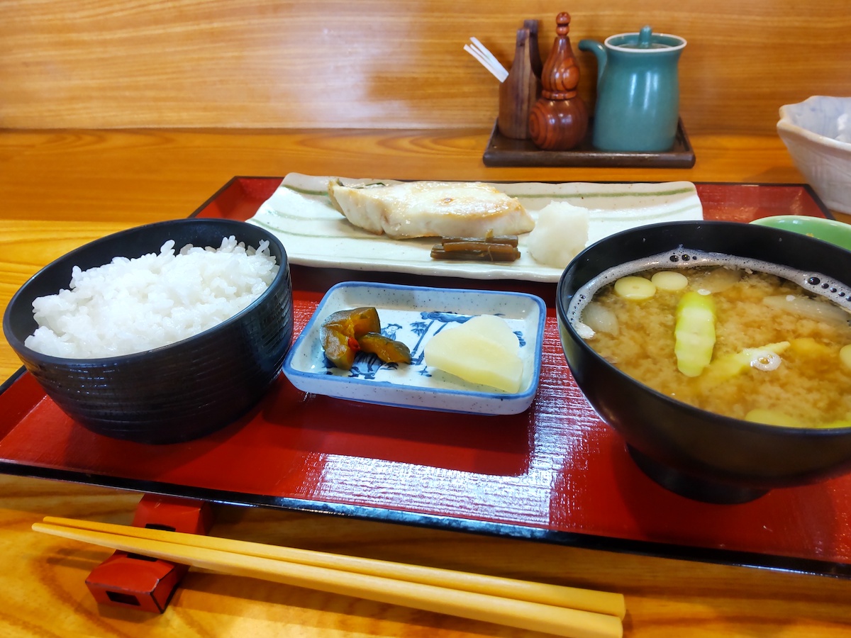 Traditional Japanese set meal with grilled fish, rice, miso soup, and pickles