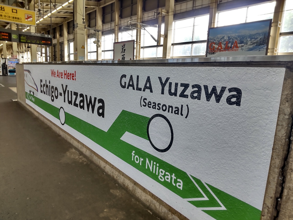 Station wall sign indicating Echigo-Yuzawa and GALA Yuzawa on a train platform