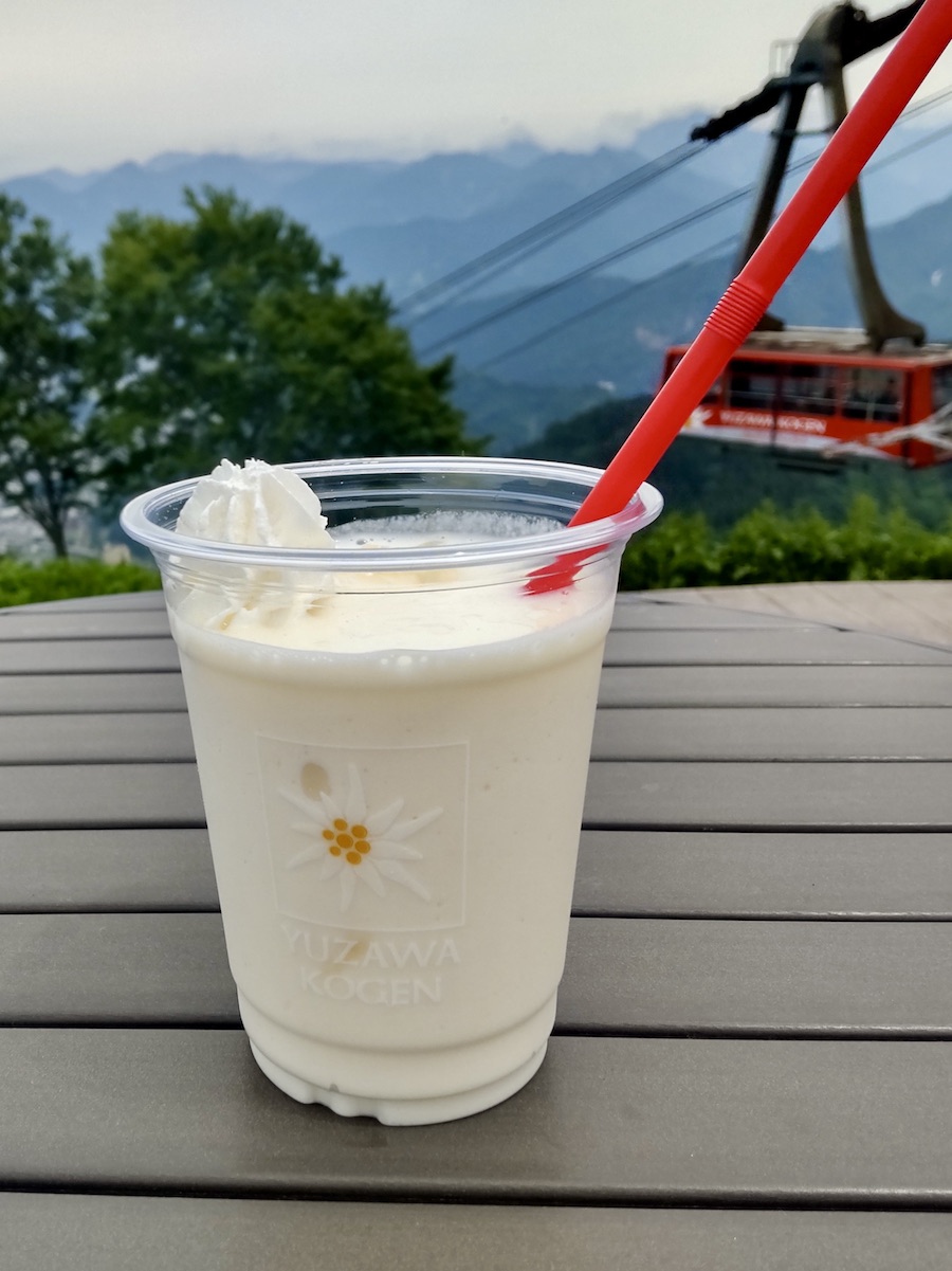 Yuzawa Kogen specialty drink against a scenic mountain and ropeway view