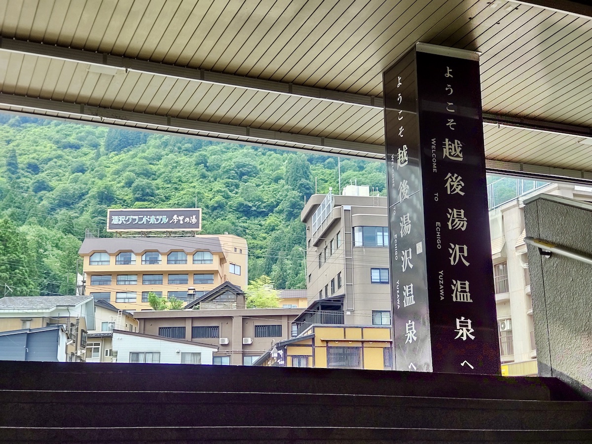 Welcome sign to Echigo-Yuzawa Onsen with green mountains in the background