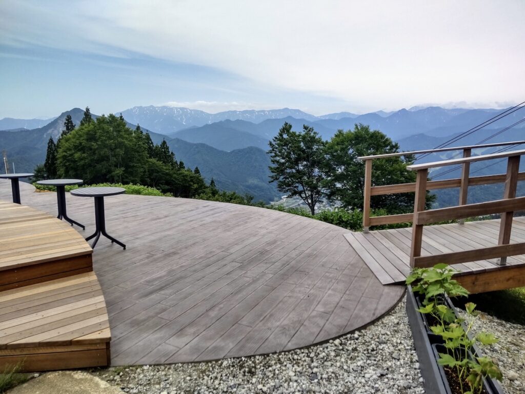 Spacious wooden terrace on a mountain peak overlooking scenic green mountain ranges