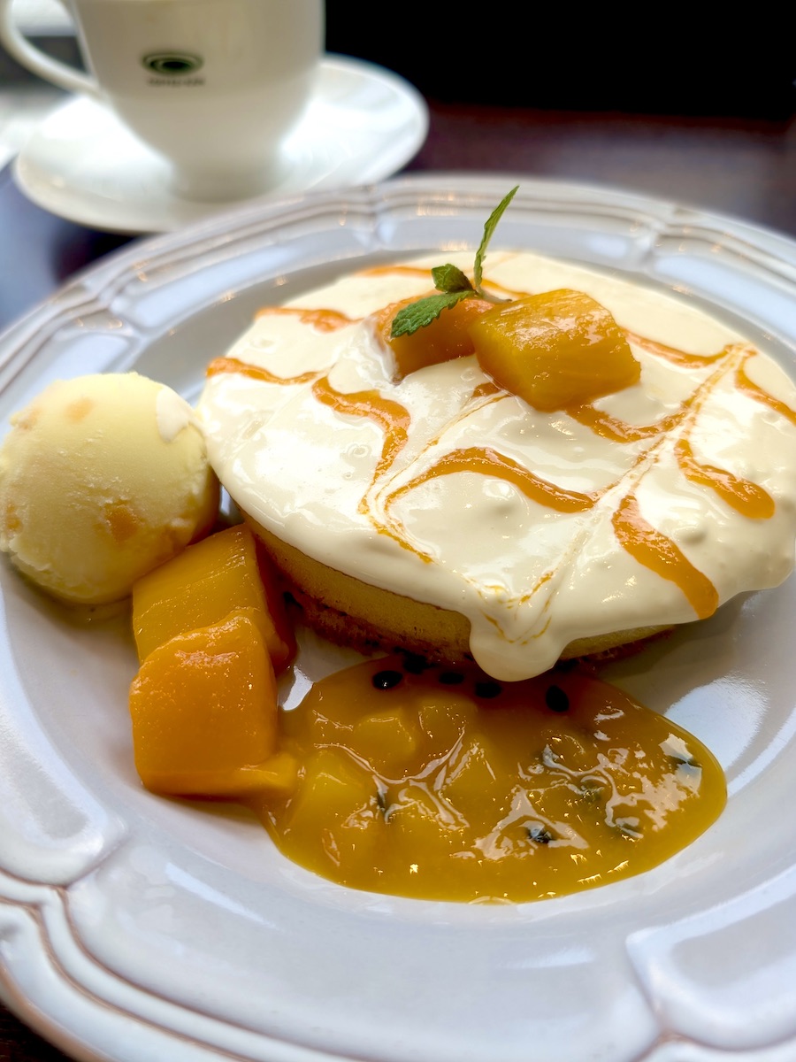 Delicious tropical mango dessert with creamy sauce and coffee cup in background
