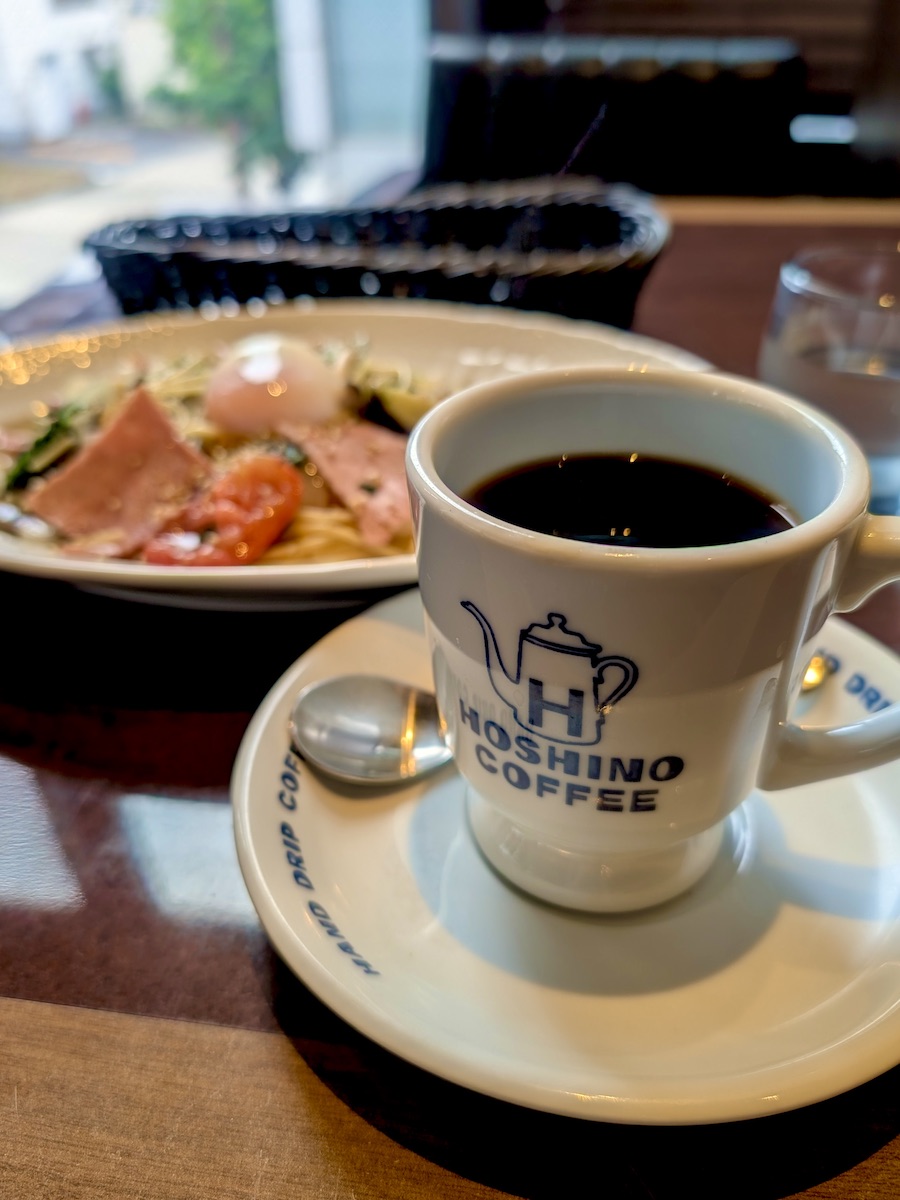 Hoshino Coffee cup served with rich topping pasta on wooden table