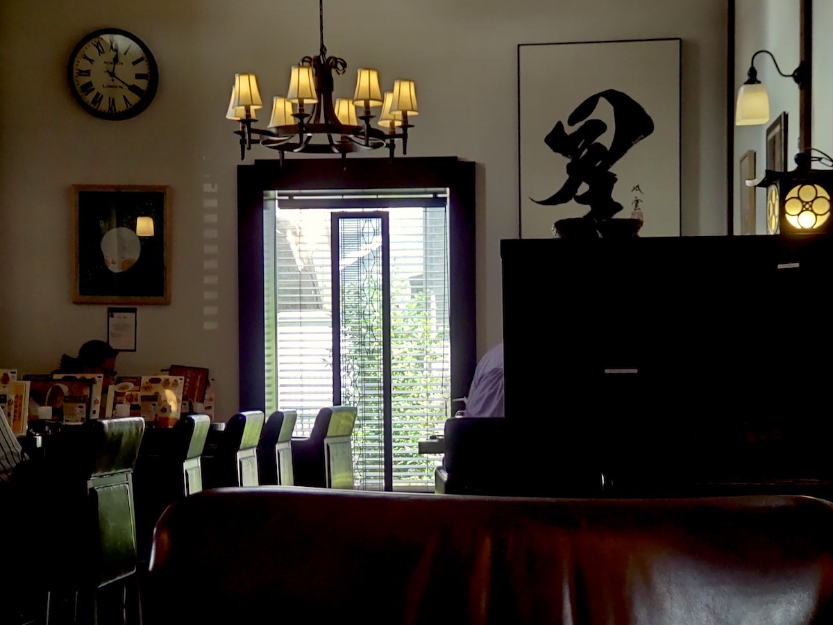 Classic Japanese cafe interior with chandelier, vintage clock, and calligraphy art