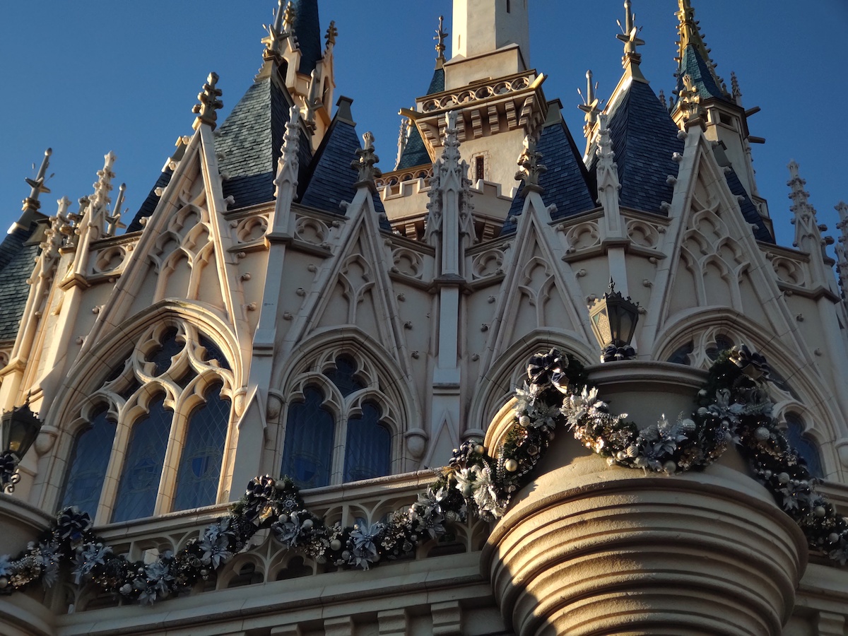 Close-up of Cinderella Castle decorated with Christmas garlands against blue sky