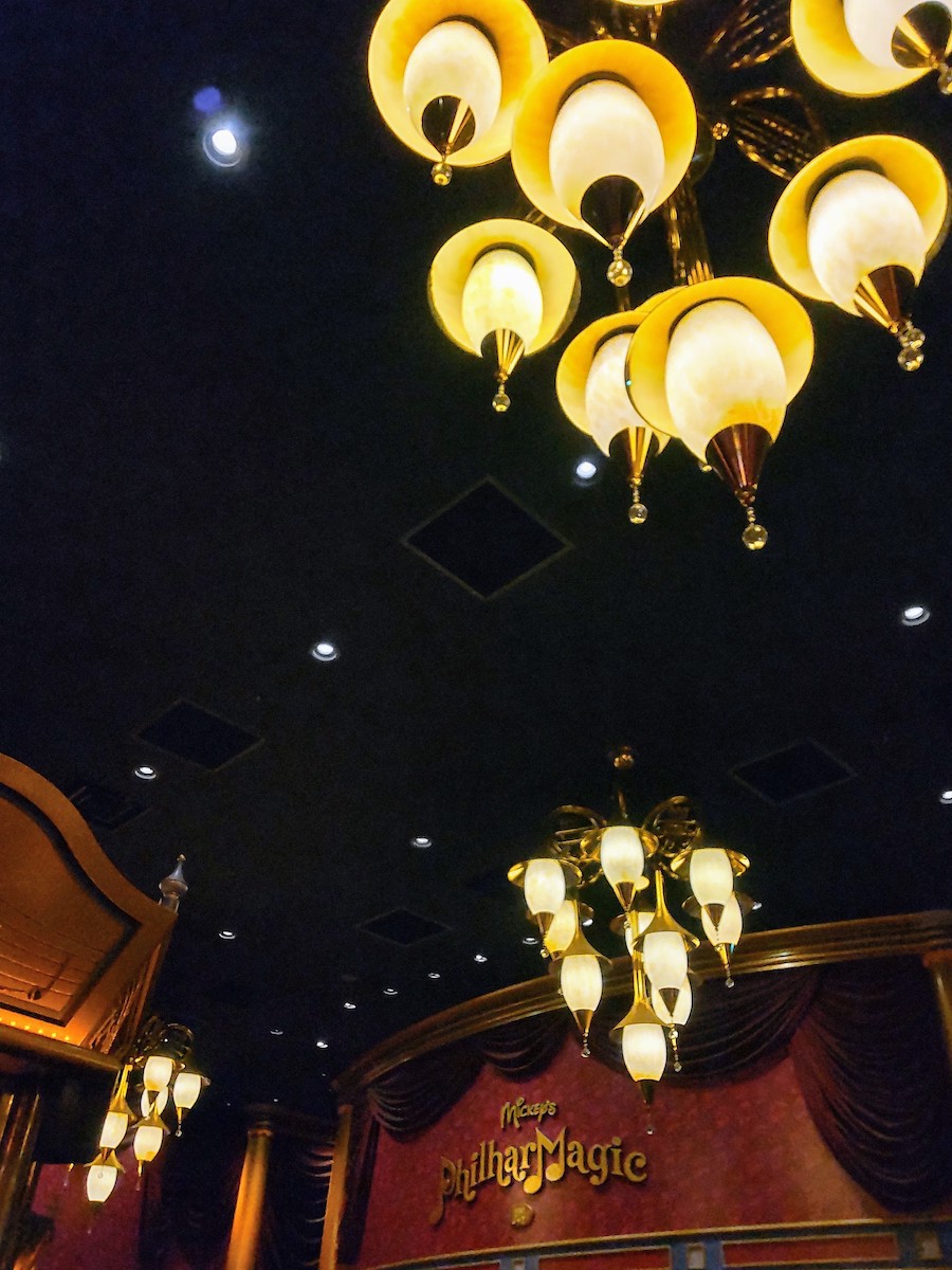 Golden glowing chandeliers decorating the dark interior of a classic theater hall