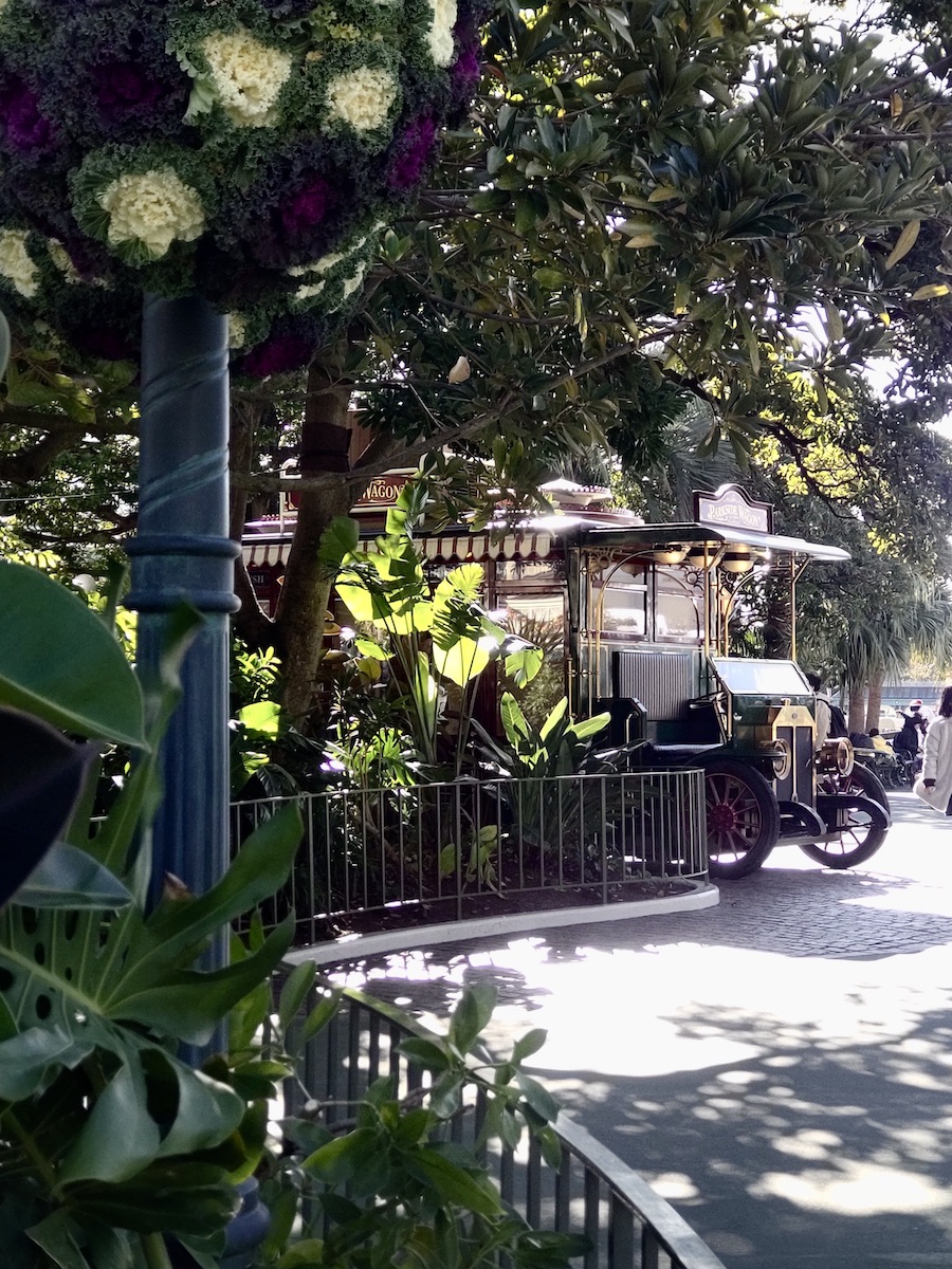 Vintage wagon parked under lush green trees with decorative winter flower arrangements