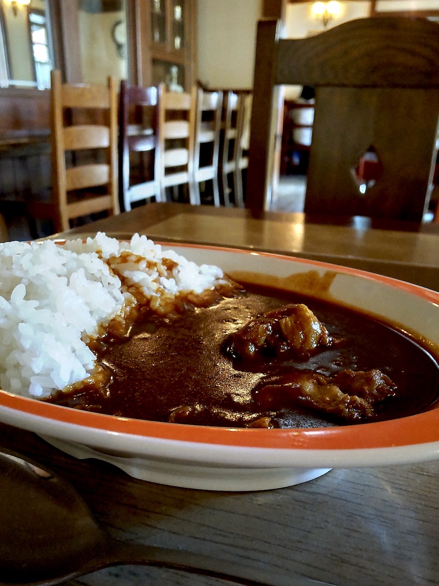Plate of rich Japanese curry rice served in a cozy wooden restaurant interior