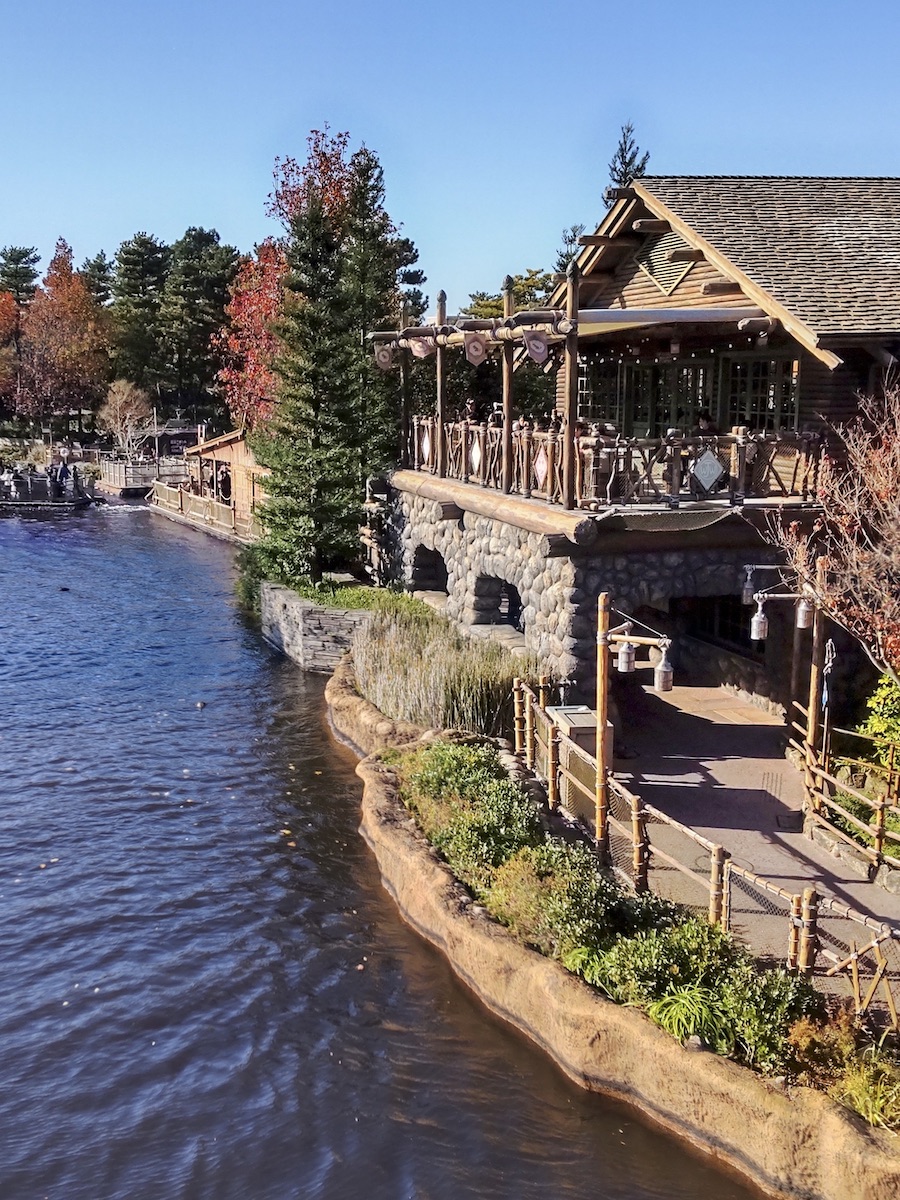 Rustic wooden lodge on the riverbank under a clear sunny blue sky